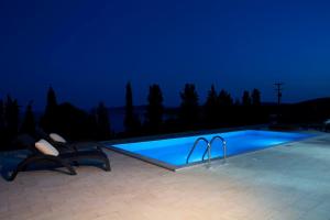 a swimming pool at night with two chairs next to it at Nema Villas in Meganisi