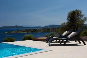 a pool with two lounge chairs next to the water at Nema Villas in Meganisi