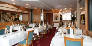 a dining room with white tables and chairs at Luitpoldpark-Hotel in Füssen