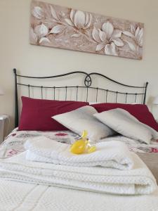 a bed with red pillows and a yellow duck on it at Casa "Rocca di Mola" in Castelmola