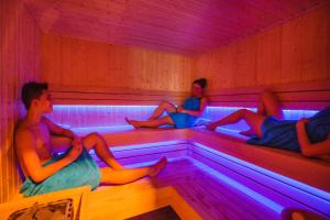 three people sitting in a room with colored lights at Apartamenty Sun & Snow Kołobrzeg Resorts z basenem in Kołobrzeg