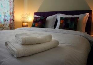 Una cama blanca con dos toallas plegables. en KorcaSmileHotel, en Korçë