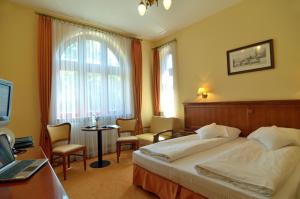 a hotel room with two beds and a television at Hotel Stefania in Krynica Zdrój