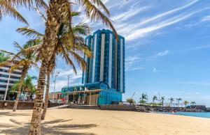 a tall blue building on the beach with a palm tree at Arrecife Gran Hotel & Spa in Arrecife