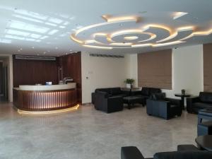 a lobby with a waiting room with couches and a large ceiling at Holyland Hotel in Amman