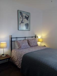 a bedroom with a bed with two lamps and a picture on the wall at Casa los Jinetes in Carmona