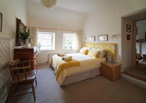 a bedroom with a large bed and a chair at Yew Tree Cottage in Bath
