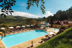 uma piscina num resort com cadeiras e guarda-sóis em Pousada Le Sapê em São Lourenço