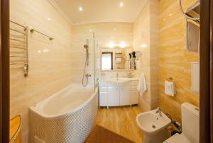 a bathroom with a tub and a sink and a toilet at Resort Hotel Karpaty in Truskavets