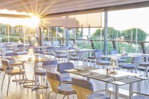 a restaurant with tables and chairs and the sun shining at Martinhal Sagres Beach Family Resort Hotel in Sagres