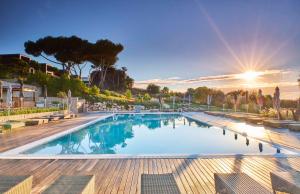 a large swimming pool with the sun in the background at Martinhal Sagres Beach Family Resort Hotel in Sagres +37 photos