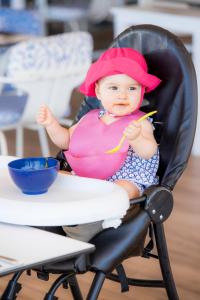 a baby in a pink hat sitting in a chair at Martinhal Sagres Beach Family Resort Hotel in Sagres