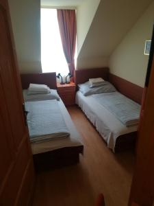 2 camas en una habitación pequeña con ventana en Áldos Panzió en Farád