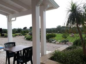 a porch with a table and chairs and a palm tree at TENUTA ALMATELLUS in Torre Lapillo