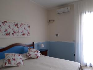 a bedroom with a bed with white sheets and a window at TENUTA ALMATELLUS in Torre Lapillo