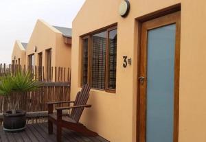 a wooden bench sitting on a deck next to a house at Walvis Bay Backpackers & Self-catering in Walvis Bay