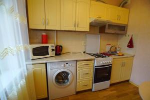 a kitchen with yellow cabinets and a stove and a microwave at Квартира in Kamianske
