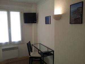 Cette chambre dispose d'une table en verre, d'une chaise et d'une fenêtre. dans l'établissement Hôtel L'Oustaou, au Lavandou