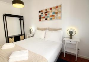 - une chambre dotée d'un lit blanc avec deux tables et un miroir dans l'établissement Sete Rios, Near Zoo Lisboa/ free Wifi, à Lisbonne