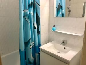 a bathroom with a blue shower curtain next to a sink at App Zeelaan A2 in Koksijde
