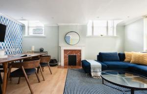 a living room with a blue couch and a table at The Kensington Palace Mews - Bright & Modern 6BDR House with Garage in London