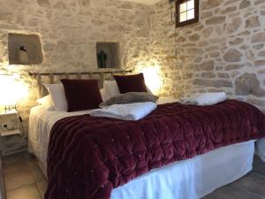 ラ・ロック・ガジャックにあるLes Hauts de Gageac Maison d'Hôtes de Charmeの石壁のベッドルーム1室(大型ベッド1台付)