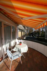 a table and chairs on a balcony with an orange canopy at Kurhotel Eichwaldeck in Bad Wörishofen
