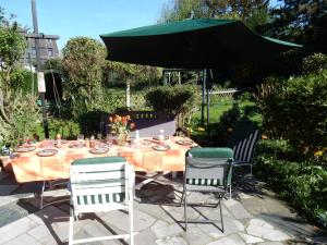 a table with a green umbrella and three chairs at Düsseldorfer Privatzimmer in Düsseldorf