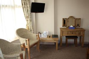 Zimmer mit einem Tisch, 2 Stühlen und einem Spiegel in der Unterkunft The Feathers in Pocklington