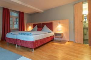 Badischer Hof في بوهل: غرفة نوم بسرير كبير مع ستائر حمراء