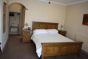 um quarto com uma cama grande com lençóis e travesseiros brancos em The Feathers em Pocklington