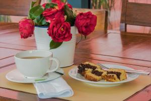 a plate of cake and a cup of coffee and flowers at Herdade do Ananás in Ponta Delgada