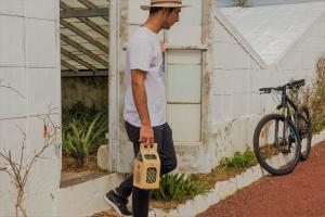a man is holding a cat bag in front of a building at Herdade do Ananás in Ponta Delgada