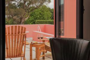 a balcony with two chairs and a table with wine glasses at Herdade do Ananás in Ponta Delgada