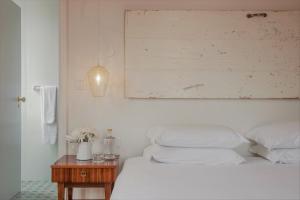 a bedroom with a white bed and a wooden table at Herdade do Ananás in Ponta Delgada