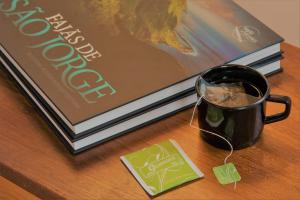 a cup of coffee on a table next to a book at Herdade do Ananás in Ponta Delgada