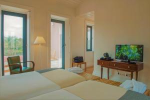 a bedroom with a bed and a desk and a television at Herdade do Ananás in Ponta Delgada