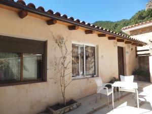 un patio con sillas blancas y una mesa frente a una casa en Río Mundo Alojamiento Rural en Riópar