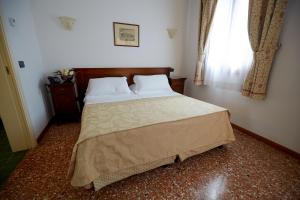 sypialnia z dużym łóżkiem z białymi poduszkami i oknem w obiekcie Hotel Riviera dei Dogi w mieście Mira