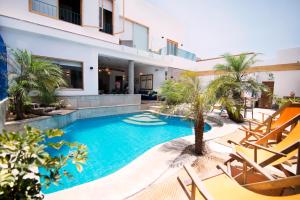 a swimming pool in front of a house with chairs and trees at Kauhuhu Casa Hotel in San Bartolo