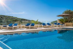 a swimming pool with lounge chairs and an umbrella at Viewpoint Boutique Living in Xlendi