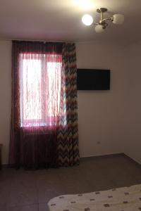 1 dormitorio con ventana y cortina roja en Inter Hotel en Ternopilʼ