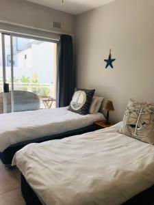 two beds sitting in a room with a window at 9 Casablance Ballito~Beach on your doorstep. in Ballito