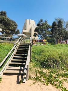 Un escalier en bois mène à un parc avec une aire de jeux. dans l'établissement 9 Casablance Ballito~Beach on your doorstep., à Ballito
