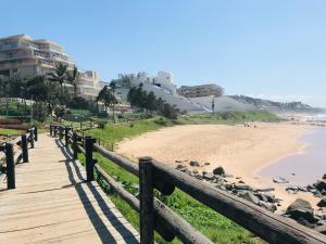 a wooden boardwalk leading to a beach with buildings at 9 Casablance Ballito~Beach on your doorstep. in Ballito