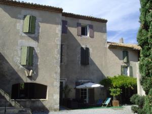 a large stone building with an umbrella in front of it at Loft du moulin de Milan in Cheval-Blanc