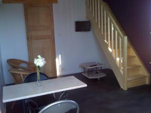 a room with a table and stairs with a vase of flowers at Loft du moulin de Milan in Cheval-Blanc