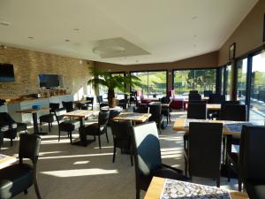 un restaurante con mesas, sillas y ventanas en Hotel Les Galets, en Criel-sur-Mer