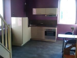 a kitchen with purple walls and a refrigerator and a table at Loft du moulin de Milan in Cheval-Blanc