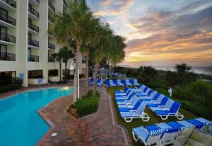 uma piscina com espreguiçadeiras e palmeiras em frente a um hotel em Sea Crest Oceanfront Resort em Myrtle Beach